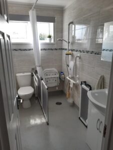 A photo of a bathroom that has been adapted to be a wet room with railings