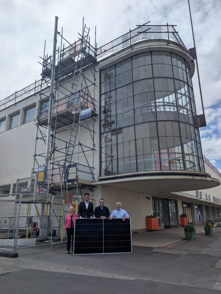From left to right pictured Cllr Kathryn Field, Dr Phil Wu, Stewart Drew, Cllr Doug Oliver stood behind a solar panel in front of the De La Warr Pavilion