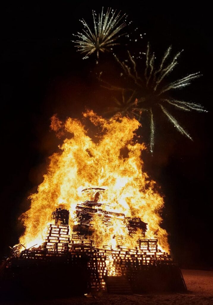 Photo of a Bonfire with fireworks above.